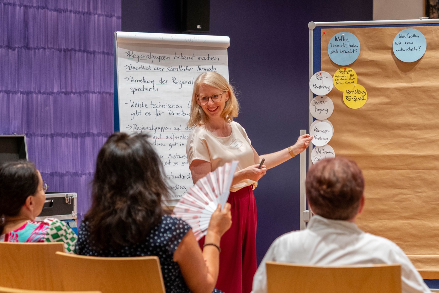 Sonja Lehmann am Flipchart im Workshop, die Gruppe sitzt im Halbkreis vor ihr
